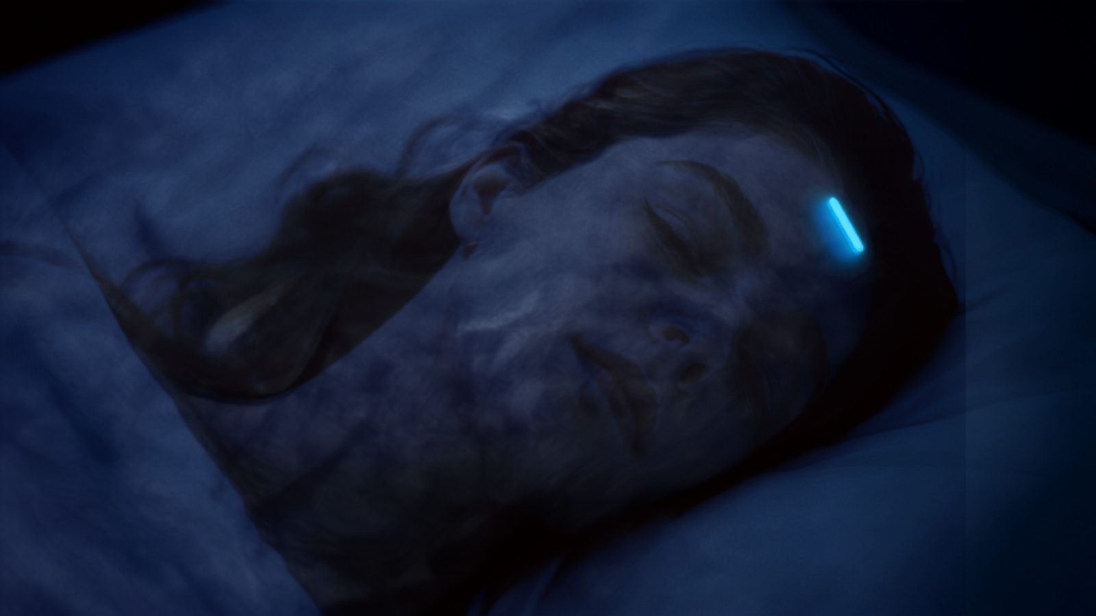 A small wearable bioelectronic patch on a person's neck with a soft blue glow suggesting brain and sleep monitoring